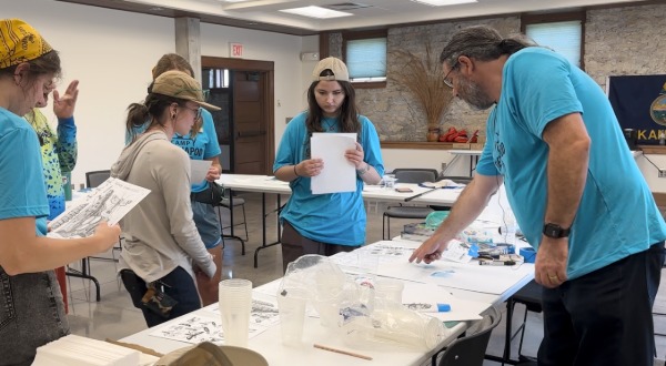 Kevin leans over transfer paper, teaching campers how to transfer printed ink to other surfaces