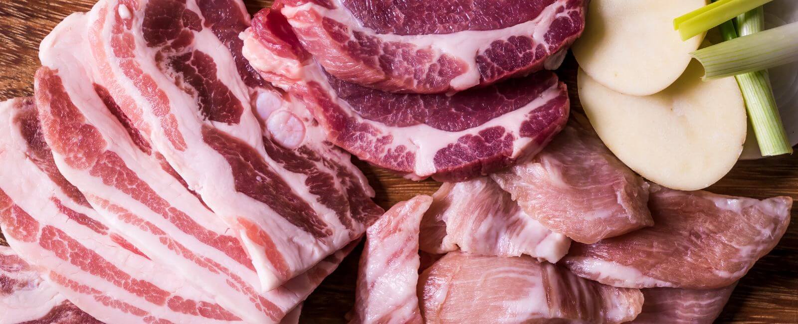 Assorted meats chopped and neatly displayed on a wooden chopping board